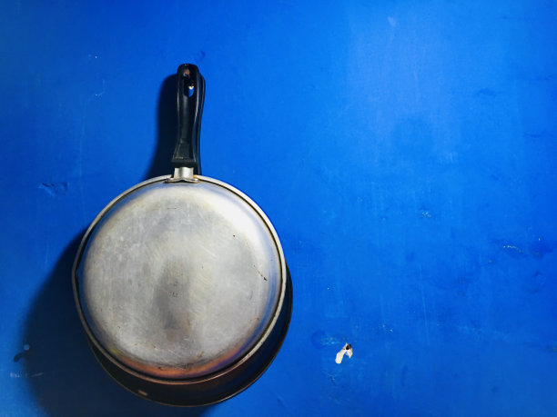 墙上的特氟龙平底锅，蓝色背景图片下载