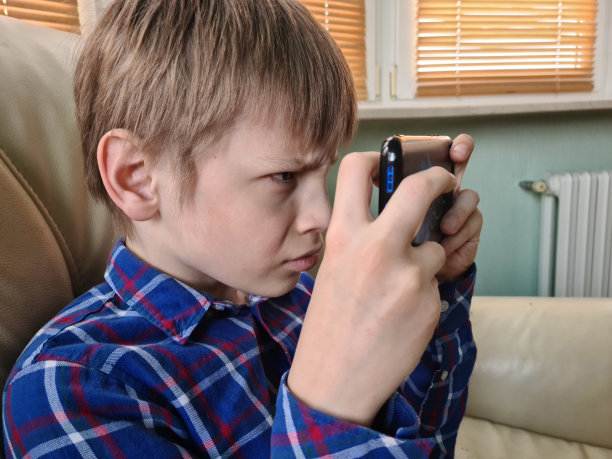 男孩使用智能手机的特写，看着屏幕，好奇的孩子手里拿着手机图片下载
