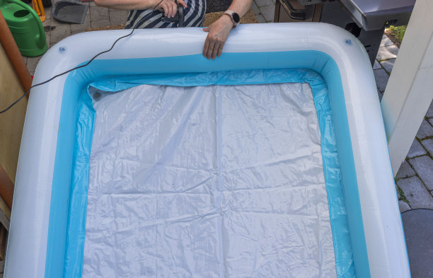 妇女用电动泵给儿童充气池充气。瑞典。图片下载