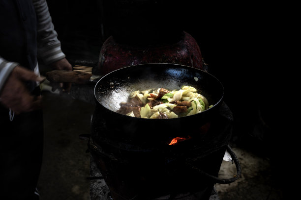 这个男人在老式炉子上用平底锅烹饪蔬菜，用柴火做饭，泰国菜图片下载
