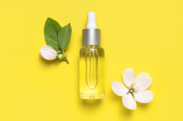 春季概念天然有机化妆品，美容草本产品水疗香薰油。干净的玻璃化妆品瓶滴管，精致的春天的花朵在黄色背景平铺顶视图。模型图片下载