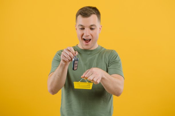 一个英俊的男子拿着一辆新车的钥匙。买新车的概念。事业上的胜利和成就。图片下载