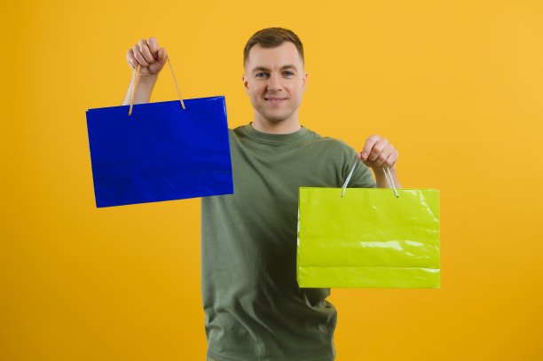 照片上的微笑夫妇拿着购物袋孤立的黄色背景。图片下载