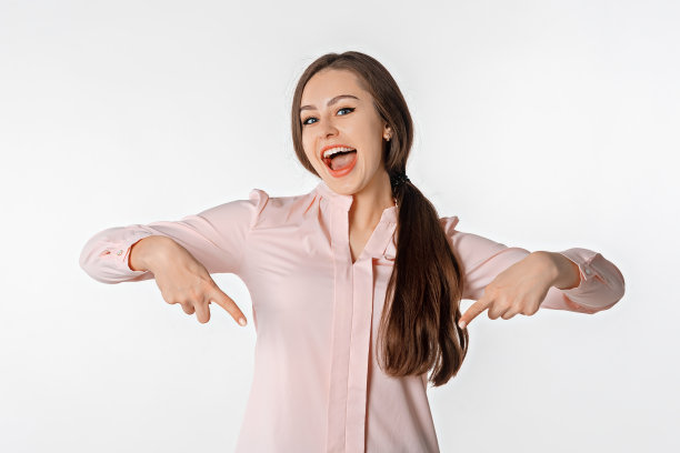 年轻的黑发女人的肖像指向向下和微笑，显示横幅，点击下面的链接手势，邀请人们跟随，站在白色背景图片下载