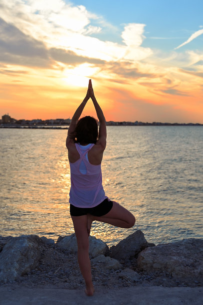 苗条的女人在海滩日落沉思的背影。图片下载