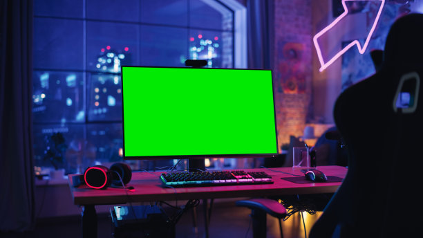 在家里玩游戏:空的游戏站与玩家的个人电脑与绿色屏幕色度键显示器站在木制桌子上的时尚阁楼公寓霓虹灯。图片下载