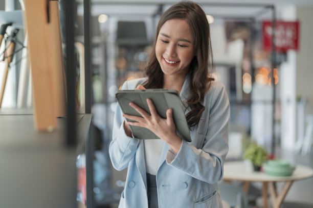 聪明自信亚洲女性创业企业家小企业主女商人穿着聪明的休闲布微笑手使用平板电脑工作库存检查在陈列室办公室白天背景图片下载