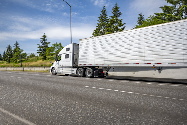 标准大卡车白色半挂车运输货物的冰箱半挂车在宽阔的多线公路上运行图片下载