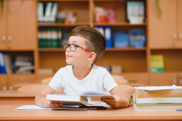 快乐的小学生坐在课桌前，教室里图片下载