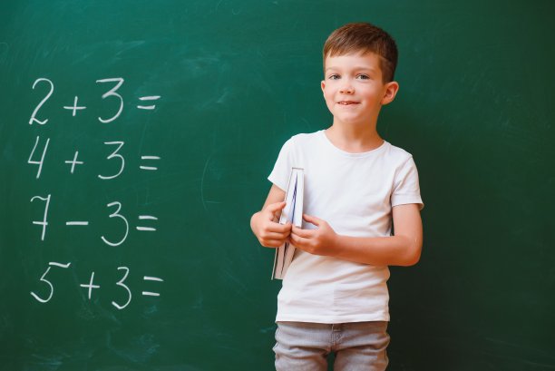 有趣的男孩在教室里的绿色学校董事会附近。小学。回到学校。图片下载