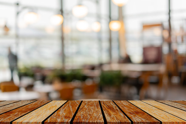 抽象模糊的现代室内酒吧餐厅与圆形散景光和现代木桌子透视显示广告，并推广内容或产品的背景图片下载