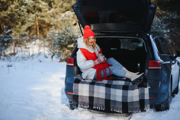 还有一杯饮料。美丽的年轻女子是在户外靠近她的汽车在冬天的时候。图片下载