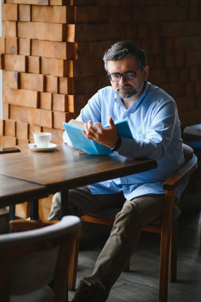 一位年长的老人在咖啡店里看书，享受着他的文学爱好图片下载
