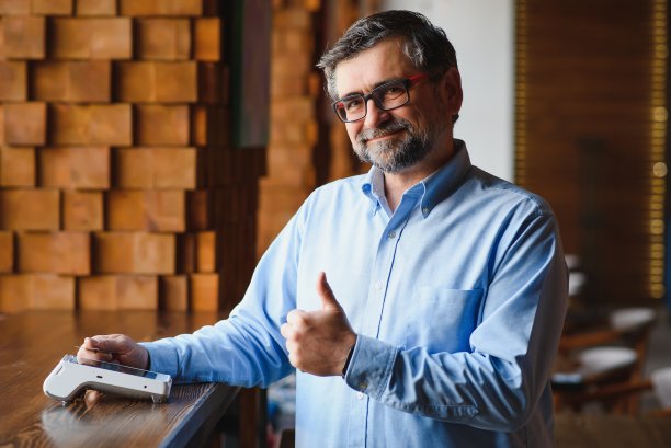 成熟的商人使用NFC技术的非接触式信用卡支付。图片下载