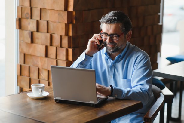 老年男性自由职业者在咖啡馆的笔记本电脑上工作。远程工作的概念。图片下载