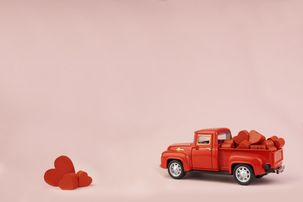 粉红色背景上有小心形的玩具车。图片下载