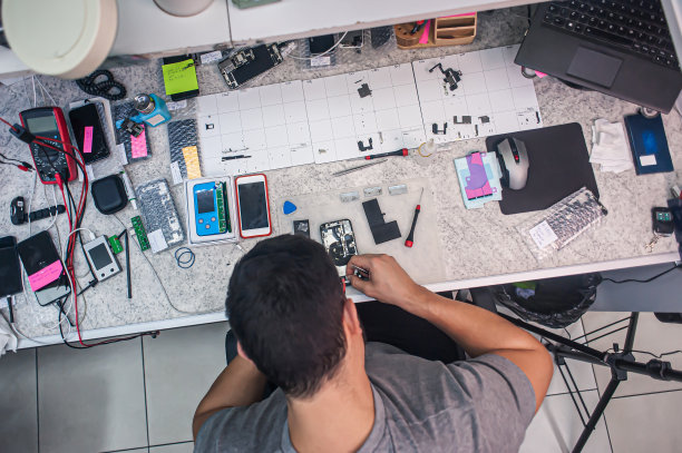 电子维修车间，技术人员被工具和设备包围着。图片下载