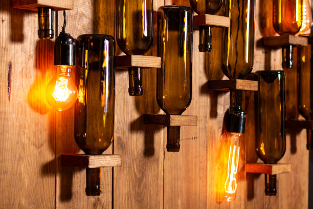 木墙上有空酒瓶和白炽灯。图片下载