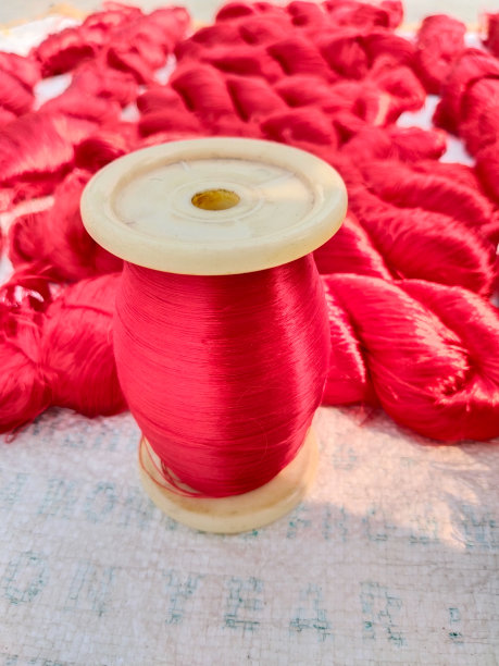 Close up Background Spool of sewing threads colorful sort   Close up Spool of sewing expensive red silk threads colorful sort with Silk background.图片下载