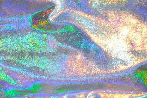 全息金属背景。金属织物纹理与彩虹渐变。壁纸有银色、紫色和绿色。金属全息材料。纹理具有彩虹色的波浪和褶皱图片下载