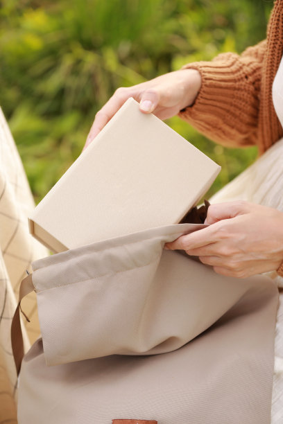 在夏季公园，一名面目人非的妇女从户外可重复使用的环保袋中拿出了带有SME纸板模型的工艺盒图片下载