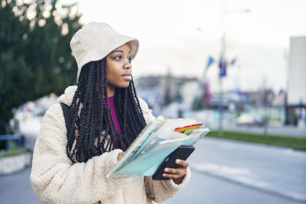 年轻的非裔美国学生在寒假探索新的城市，她试图用她的地图和导游找到旅游景点图片下载