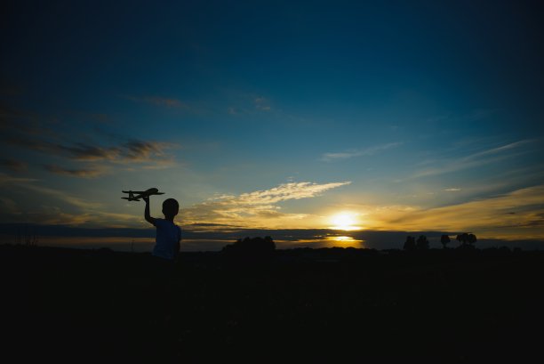 梦想着飞翔。快乐童年的概念。两个女孩在日落时玩玩具飞机。孩子们在太阳的背景与一架飞机在手中。孩子们在飞机上玩耍的剪影。图片下载