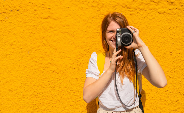 一名妇女正在拍摄一张黄色背景的照片图片下载