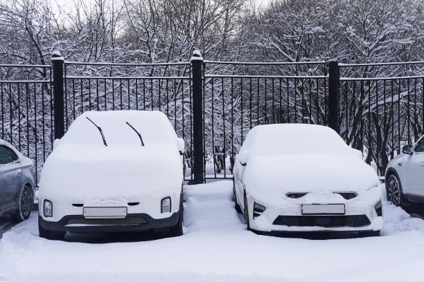 寒冷的冬天，停车场里被雪覆盖的汽车图片下载