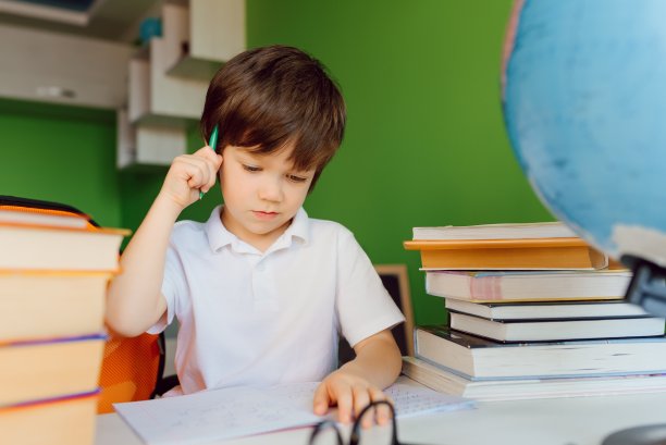 男孩在家里学习，做作业。远程教育，在线教育。图片下载