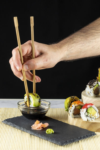 人的手在酱油中蘸寿司卷图片下载