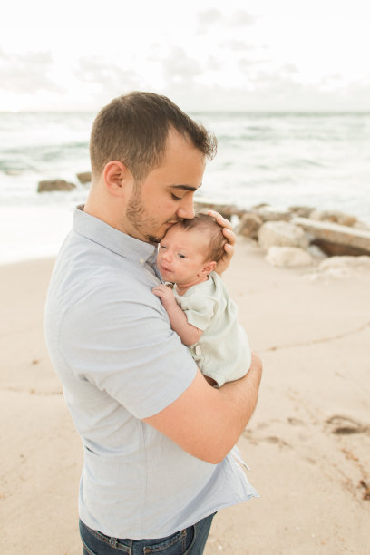 2022年11月，佛罗里达州棕榈滩海岸，一位年轻的父亲在金色日出时依偎着他刚出生的儿子图片下载