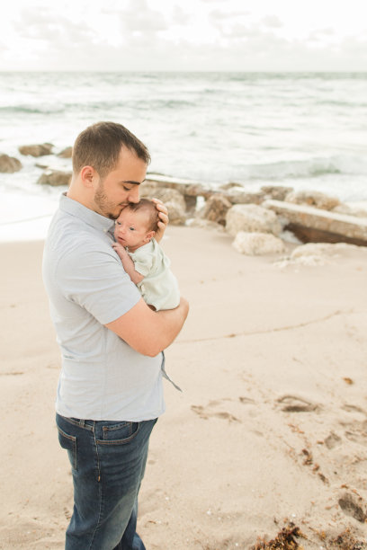 2022年11月，佛罗里达州棕榈滩海岸，一位年轻的父亲在金色日出时依偎着他刚出生的儿子图片下载