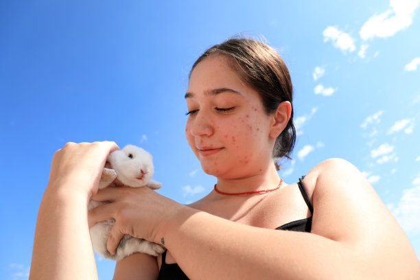十几岁的女孩在阳光明媚的天空抱着小兔子的肖像图片下载