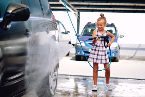 一个穿着夏装的漂亮小女孩帮她的父母洗车的特写图片下载