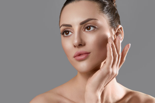 皮肤护理。女人与美丽的脸触摸健康的面部皮肤肖像。美丽的微笑的女孩模型与自然妆容感动水皮肤特写图片下载