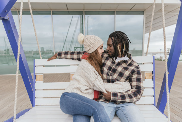 相爱的多民族情侣坐在秋千上图片下载