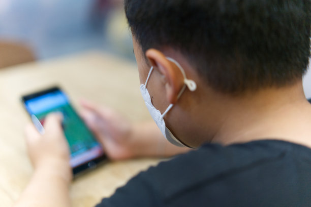 男孩看手机在手中的高角度后视图，选择性聚焦图片下载