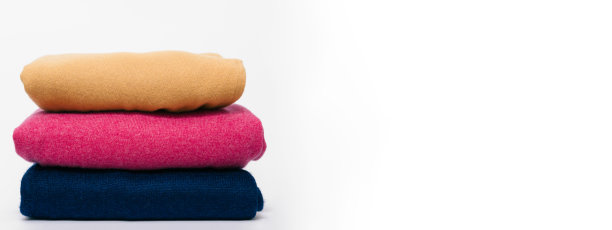 三件羊毛衫的横幅黄色，品红和蓝色躺在白色孤立的背景。概念洗衣，冬季衣柜。空白的地方为您的设计图片下载