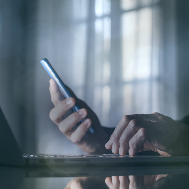 商人在笔记本电脑上用手机工作。技术，商业，金融和市场，概念。图片下载