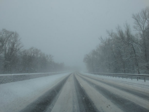 在暴风雪中开车。透过驾驶玻璃，能见度很低，路面覆盖着冰雪。冬天的极端天气。冬天,暴雪。图片下载
