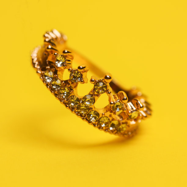 金色的戒指皇冠漂浮在黄色的背景与阴影图片下载