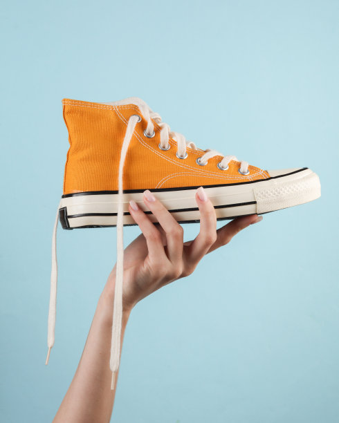 黄色复古运动鞋在一个女人的手在蓝色的背景图片下载
