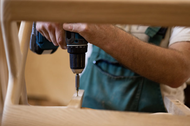 男木匠在木结构上工作时使用钻头的特写。图片下载