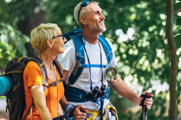 成年夫妇背着背包和登山杖在森林里徒步旅行。图片下载
