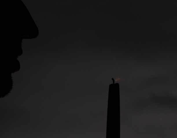 男性剪影与蜡烛光与黑暗的背景图片下载