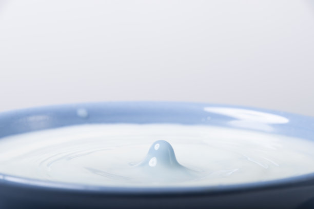 将新鲜的蓝色牛奶滴入白色背景的杯子中图片下载