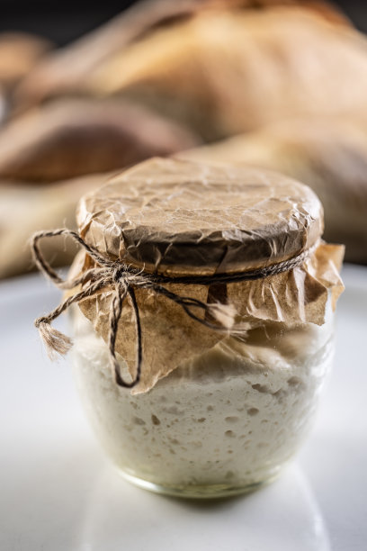 一罐自制的黑麦酸面包，背景是新鲜的面包。图片下载