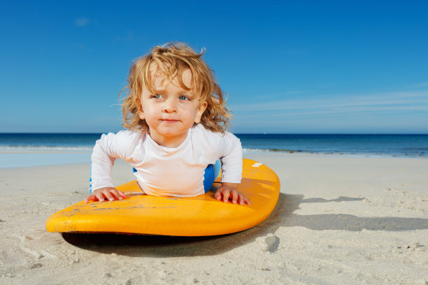 美丽的小女孩在海滩上学习站在冲浪板上图片下载