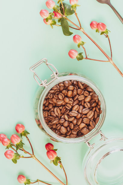 有机咖啡豆装在玻璃罐里，还有红色的花朵图片下载